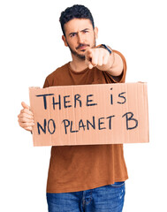 Young hispanic man holding there is no planet b banner pointing with finger to the camera and to you, confident gesture looking serious