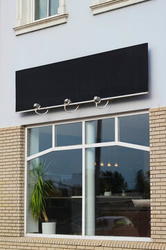Clear signboard banner on a storefront mock up template for business logo and branding. Blank black restaurant or shop signboard copy space mockup.