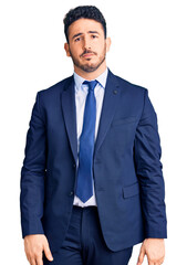 Young hispanic man wearing business clothes with serious expression on face. simple and natural looking at the camera.