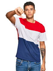 Young handsome african american man wearing casual clothes looking unhappy and angry showing rejection and negative with thumbs down gesture. bad expression.