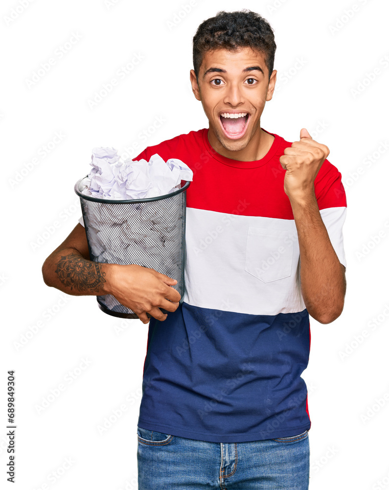 Canvas Prints Young handsome african american man holding paper bin full of crumpled papers screaming proud, celebrating victory and success very excited with raised arms