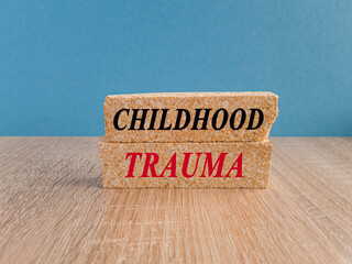 Concept red words Childhood trauma on brick blocks. Beautiful wooden table, blue background....