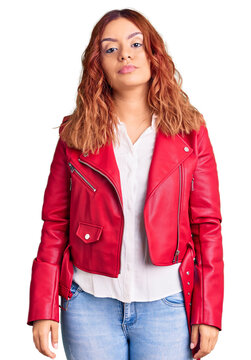 Young latin woman wearing red leather jacket with serious expression on face. simple and natural looking at the camera.