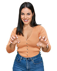 Young hispanic woman wearing casual clothes smiling funny doing claw gesture as cat, aggressive and...