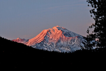 Warm rays of sunset hit Mt Shasta and the smaller cone of Shastina to the left