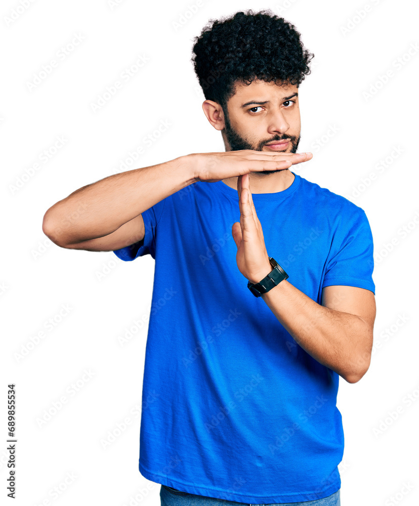 Wall mural Young arab man with beard wearing casual blue t shirt doing time out gesture with hands, frustrated and serious face