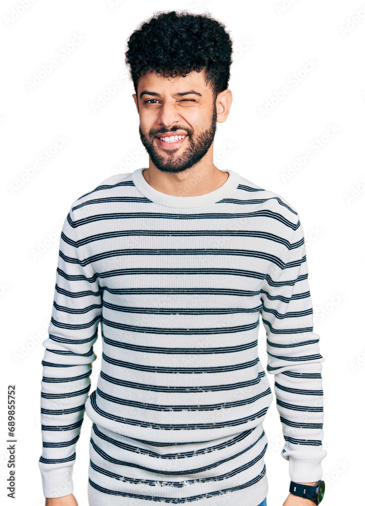 Canvas Prints young arab man with beard wearing casual striped sweater winking looking at the camera with sexy exp