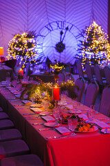 decorated New Year's table with a candle on the background of a New Year tree and a clock