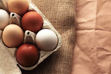 different colored chicken eggs in a box on a burlap background, easter