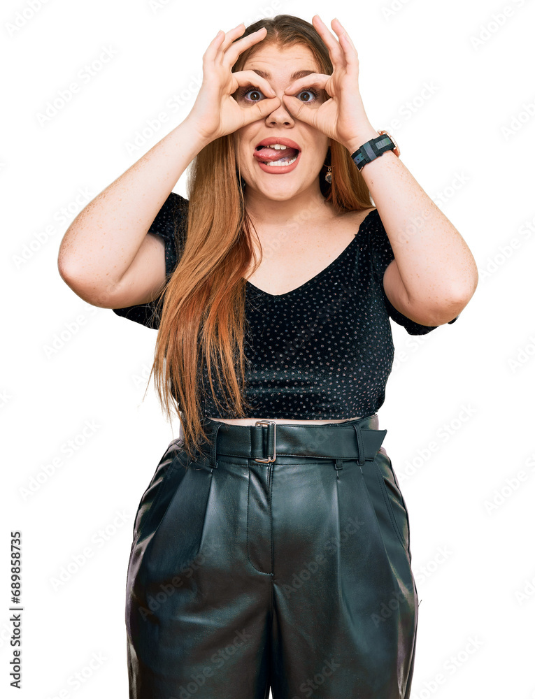 Sticker Young beautiful redhead woman wearing elegant clothes doing ok gesture like binoculars sticking tongue out, eyes looking through fingers. crazy expression.