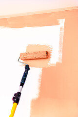 Painting and refreshing the wall with peach buzz color paint using roller, color of the year 2024