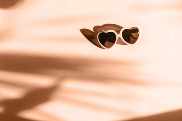 Trendy pantone Peach Fuzz color of Year 2024 background. Heart sunglasses on bright light peach...