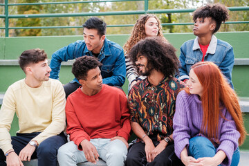 Friends with ethnic diversity gathered talking and having fun outdoors. Concept: friends