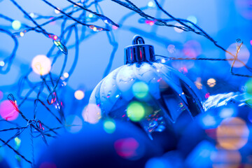 Christmas and New Year blue color baubles decoration background with colourful lights of garlands....