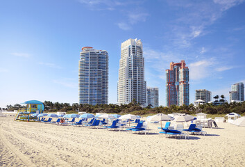 Miami South Beach with beach chairs and umbrellas , blue sky , and view of skyline condos and hotels