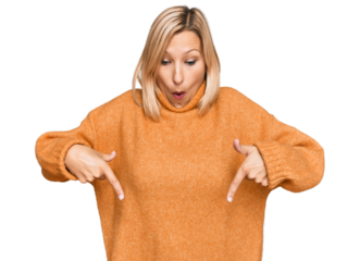 Middle age caucasian woman wearing casual winter sweater pointing down with fingers showing advertisement, surprised face and open mouth