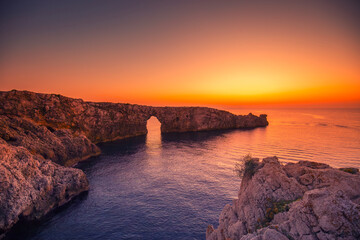 Krajobraz morski, pomarańczowy zachód słońca, skaliste wybrzeże wyspy Minorka (Menorca),...