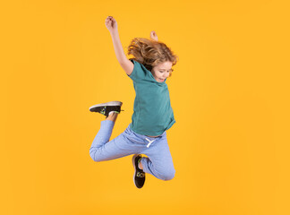 Full body of little child jump wear casual t-shirt and jeans isolated on yellow background.