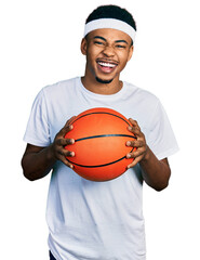 Young african american man holding basketball ball celebrating crazy and amazed for success with open eyes screaming excited.