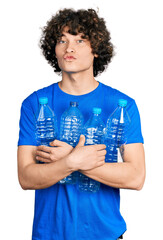 Caucasian teenager holding recycling plastic bottles looking at the camera blowing a kiss being...