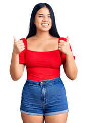 Obraz premium Young beautiful asian girl wearing casual clothes success sign doing positive gesture with hand, thumbs up smiling and happy. cheerful expression and winner gesture.