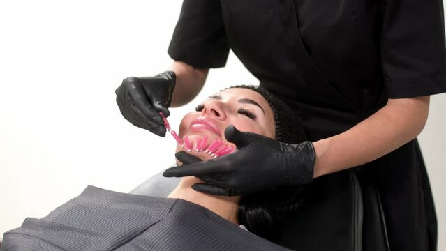 Woman undergoes a face lift procedure. Facial skin care, anti-aging face contour correction. The beautician implants cosmetic threads under the skin to relieve facial ptosis. 