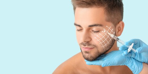 Handsome man receiving filler injection on light blue background with space for text. Skin care...