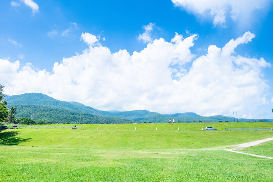 Landscape view of green grass on slope with clouds and blue sky.