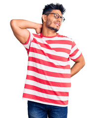 Handsome latin american young man wearing casual clothes and glasses suffering of neck ache injury, touching neck with hand, muscular pain