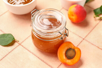 Jar with sweet apricot jam on pink tile background
