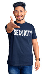 Handsome latin american young man wearing security t shirt smiling friendly offering handshake as greeting and welcoming. successful business.