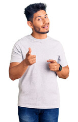 Handsome latin american young man wearing casual tshirt pointing fingers to camera with happy and funny face. good energy and vibes.