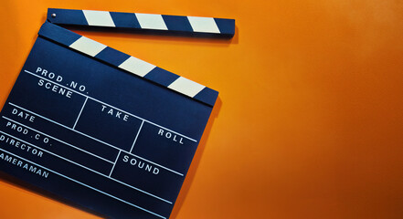 Fototapeta na wymiar A clapperboard with an orange background. Symbol of filmmaking and video production. Professional type of equipment, used on films to assist in synchronizing of picture and sound