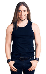 Fototapeta premium Young adult man with long hair wearing goth style with black clothes with a happy and cool smile on face. lucky person.