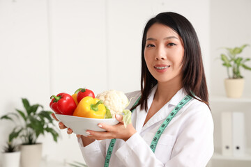 Female Asian nutritionist with healthy food in office