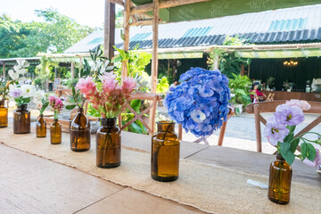 Blue Hydrangea flowers in vase on wooden table at outdoor restaurant.