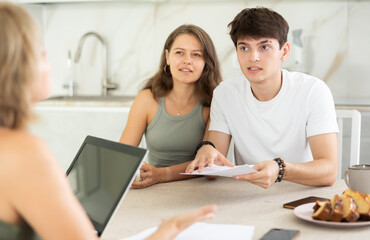 Young girl and guy are talking to woman real estate sales manager. Woman talks about advantages of...