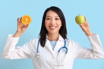 Female Asian nutritionist with fruits on blue background