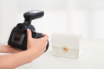 Female photographer taking photo of fashionable purse in studio