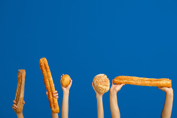 Female hands holding loaves of different fresh bread on blue background