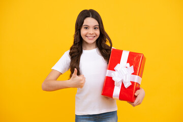 Fototapeta premium Happy teenager, positive and smiling emotions of teen girl. Child with gift present box on isolated studio background. Gifting for kids birthday.