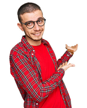 Hispanic young man wearing casual clothes inviting to enter smiling natural with open hand