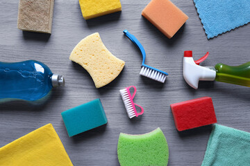 Background with cleaning tools. Kitchen sponges, brushes, detergent, window spray, rags on a wooden...