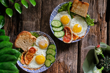 breakfast. Fried eggs with fried cheese, cucumber. Wooden background, top view