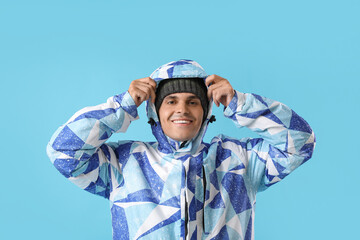 Young man in winter clothes on color background