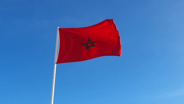 low angle view of the kingdom of Morocco Flag waving with wind against blue sky - Moroccan flag waving 