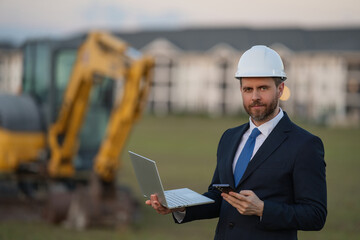 Civil engineer worker at a construction site. Engineer man in front of house background. Confident...