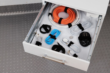 Drawer with cables tidy in a garage cabinet.
