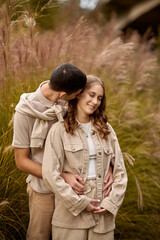 Happy couple on autumn walk outdoors. Two lovers in autumn park. Love and tender touch. Gentle hugs. Young man and woman in classic autumn colors outfit on a romantic date in a cozy park. Young girl