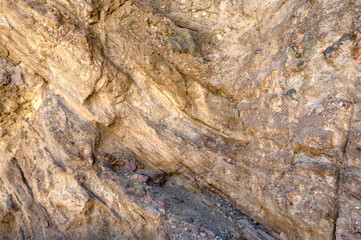 Textured background of rough uneven surface of stone with variety of colors and cracks. Geology concept 